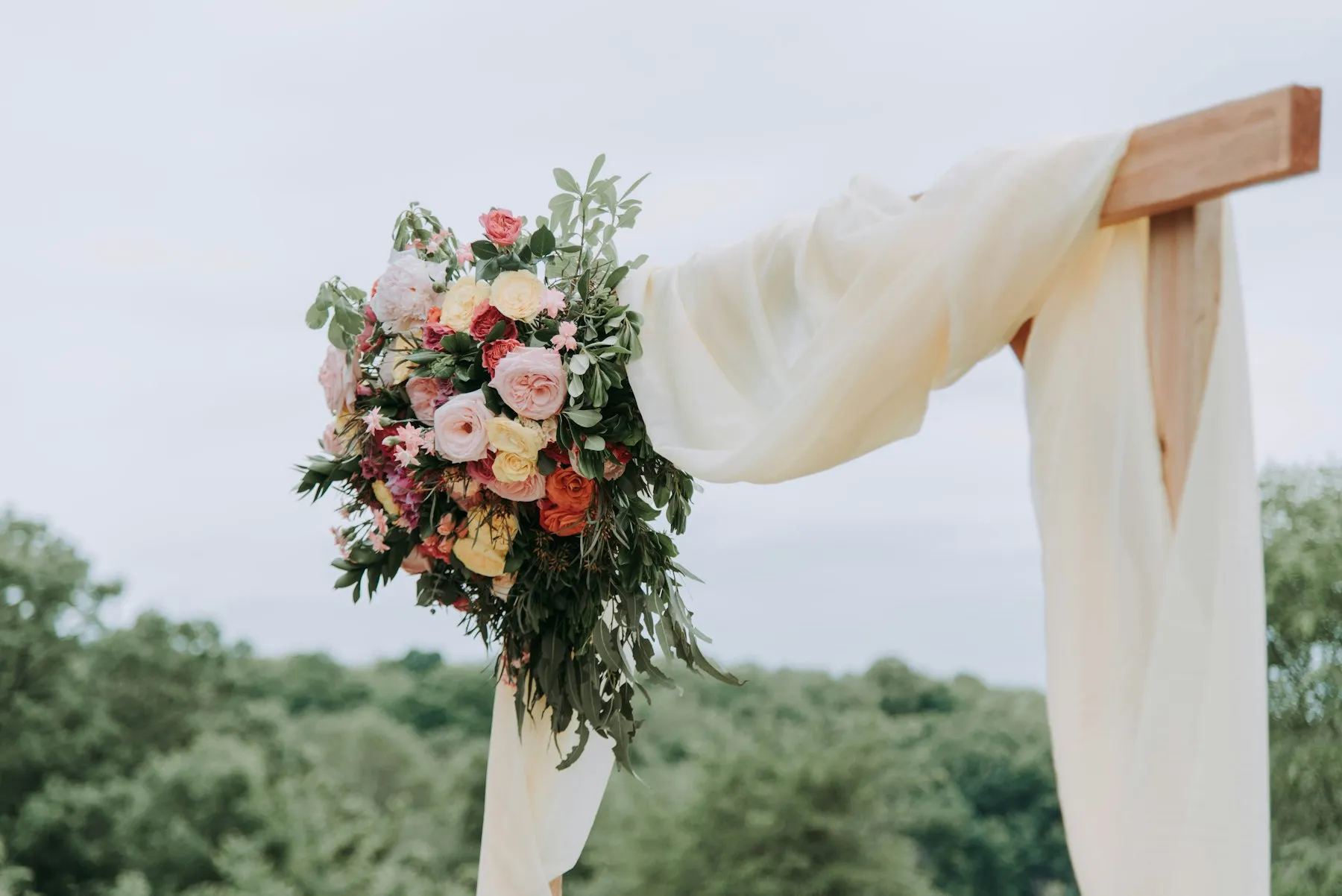 Floral ceremony arch styled with draped fabric